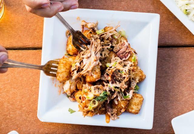 Two hands using forks to grab food off a plate in the center